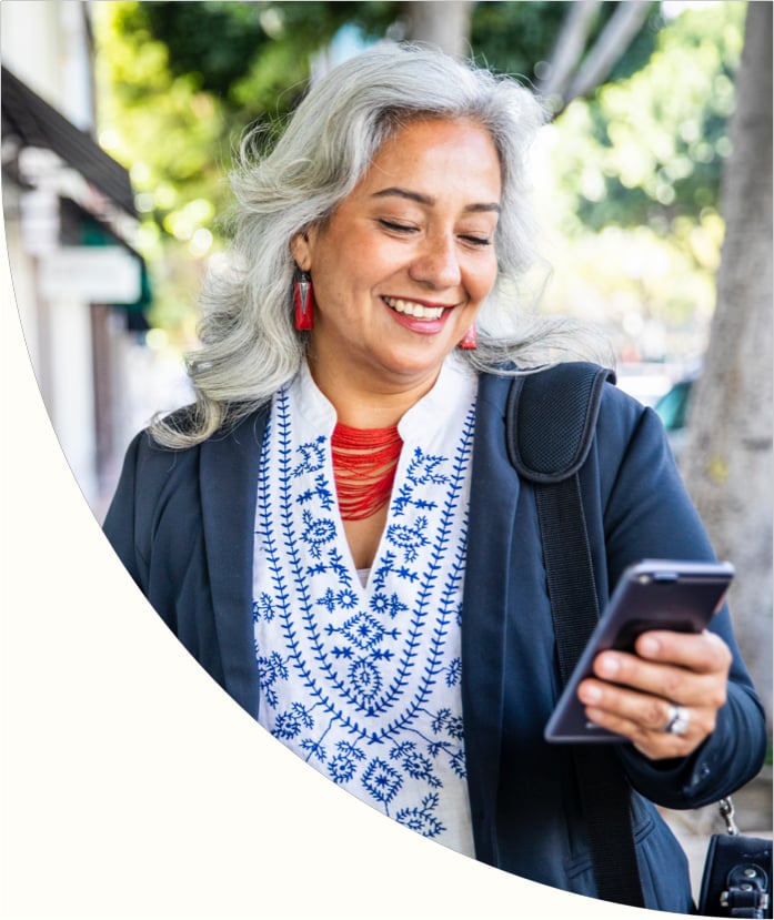 woman outside smiling at cell phone in hand