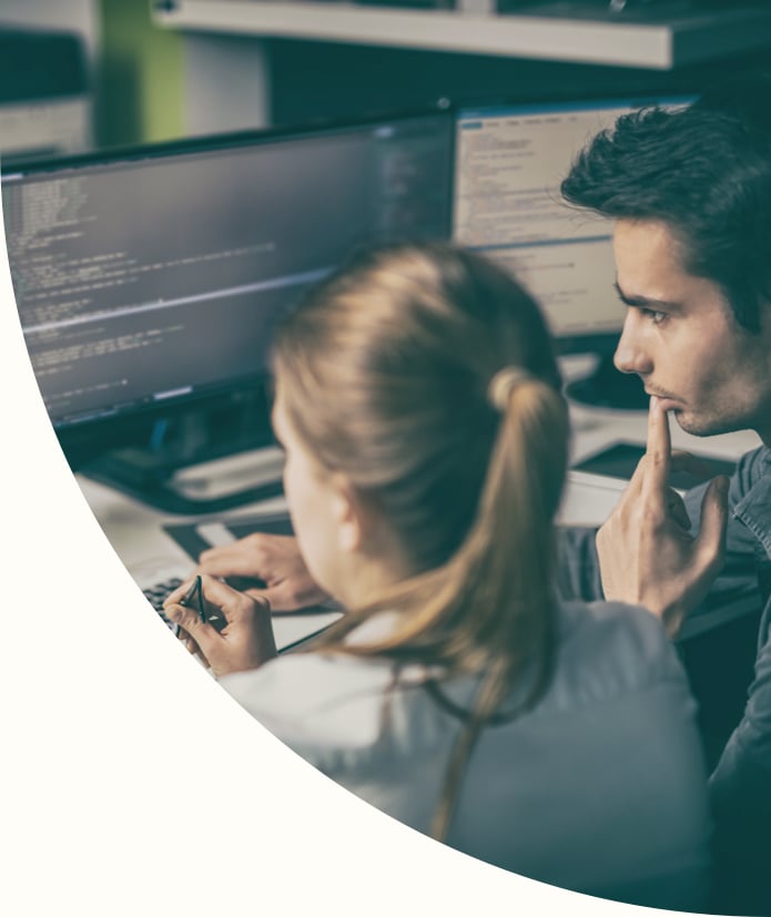 coworkers studying computer screens together discussing cybersecurity