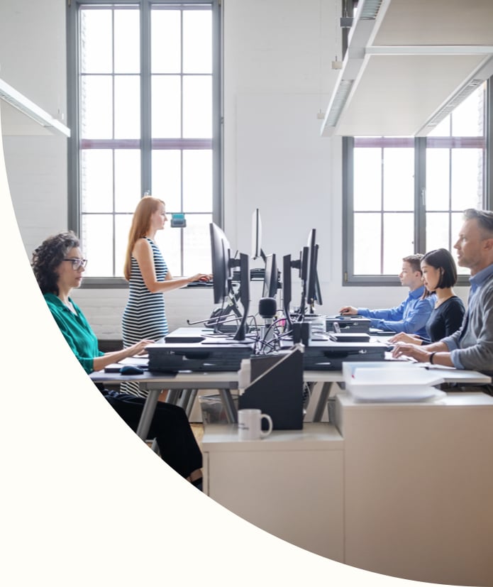 Business people at their desks in a busy, modern, open plan office.