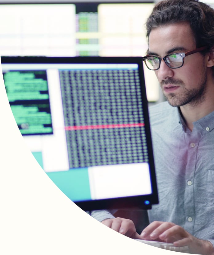 male researcher sitting at desktop computer analyzing data