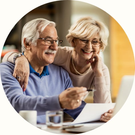 Happy senior couple going through home finances and using laptop at home