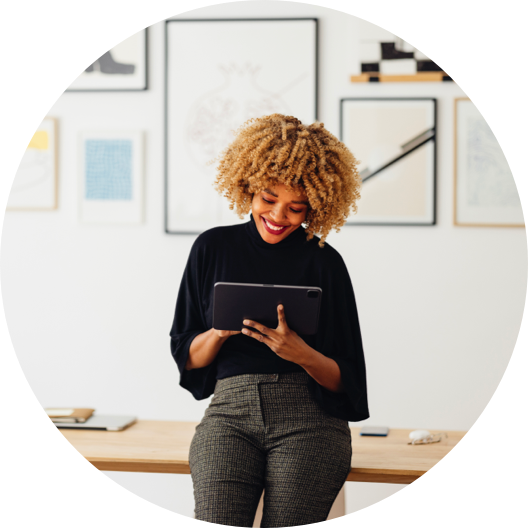 Smiling African-American Woman Standing in an Office and Looking at a Digital Tablet